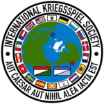 Logo of the IKS, showing the globe and classical Kriegsspiel pieces in the center, surrounded by a circle of national flags and "International Kriegsspiel Society – Aut Caesar Aut Nihil Alea Iacta Est" on the outer ring.