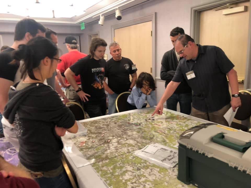 Several players and umpires standing around a table with a large map.