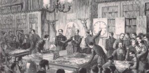 Officers standing around a table with modelled terrain and unit blocks, with a sight protection screen in the middle of the table. One officer is adjusting a big clock, while others sit in the foreground watching.